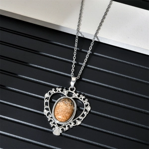Détail macro du pendentif cœur en filigrane argenté avec pierre jaspe sur fond rayé