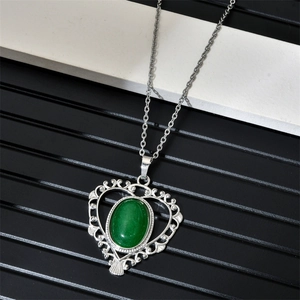 Detail of silver heart-shaped hollow pendant with green oval gemstone on O-chain necklace