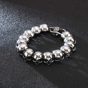 Macro shot of silver stainless steel skull beads bracelet with polished finish and square clasp