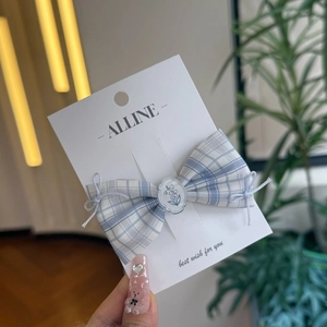 Blue and white checkered bow hair clip with flower accent on display card