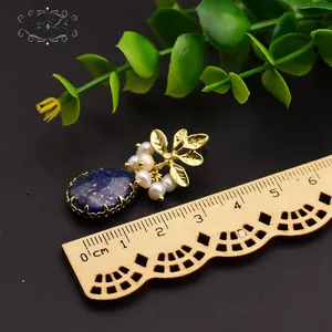 Macro detail of drop-shaped blue stone and pearl earring with measuring scale