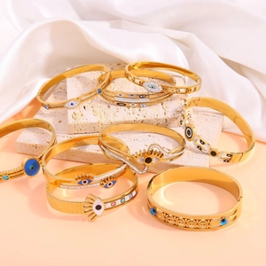 Detail of eight gold-plated stainless steel Evil Eye bracelets on beige stone