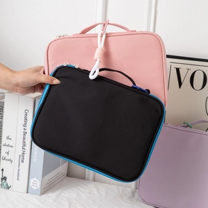 Detail of laptop sleeve handle and double zipper on pink, black, and purple bags