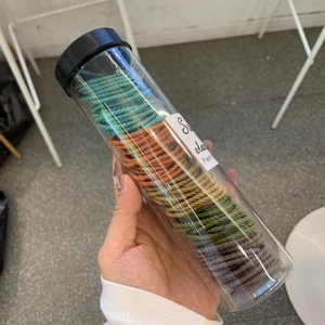 Detail view of colorful spiral elastic hair ties in a clear cylindrical packaging tube