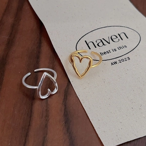 Detail of minimalist gold and silver hollow heart open rings on a textured background