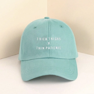 Detailed white embroidery on mint green washed cotton baseball cap featuring thick thighs text