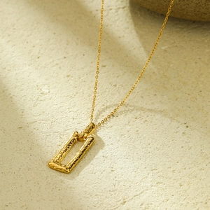 Macro detail of 18K gold plated stainless steel necklace with hammered texture pendant