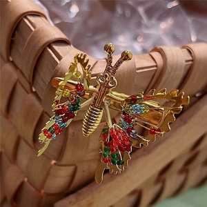 Close-up of golden butterfly hair clip with colorful beads on a woven basket edge