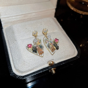 Macro detail of heart earrings with multi-colored crystals and pearls in a jewelry box