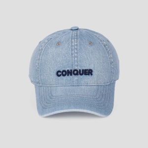Close-up of CONQUER embroidery and washed denim texture on a light blue baseball cap
