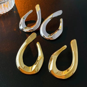 Abstract liquid metal U-shape earrings in gold and silver finish on black background