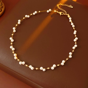 Close-up of double-layer French pearl necklace with golden beads on leather surface