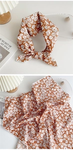 Detail of square scarf with orange floral pattern shown tied and flat on white surface
