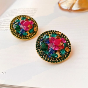 Retro round gold ear clips featuring vibrant colorful crystals on a magazine background