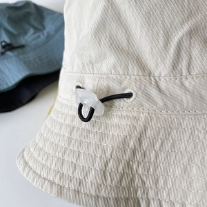Detail of nylon bucket hat with adjustable elastic drawstring and reinforced brim stitching