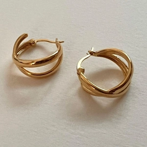 Detail of gold-plated triple layer interlocking hoop earrings on white background