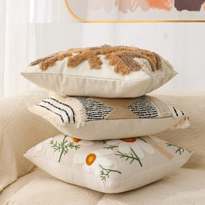 Detail of stacked bohemian tufted pillows with geometric patterns and daisy embroidery