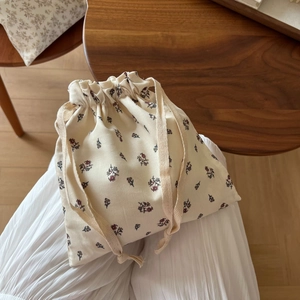 Detail of floral drawstring cotton bag showing texture and red flower pattern on beige fabric