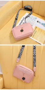Close-up of pink textured crossbody bag with metal cat pendant and woven strap