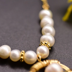 Handmade necklace with natural freshwater pearls and gold beads on a dark background