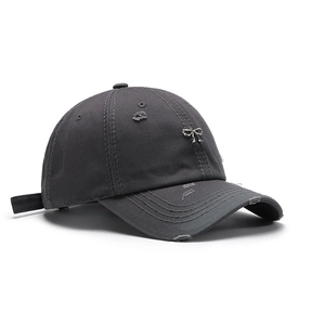 Distressed dark gray baseball cap with ripped details and a silver metal bow pendant