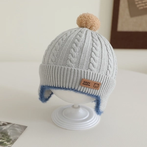Detailed knit pattern on gray baby earflap hat with blue plush lining and brown patch