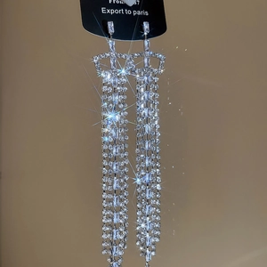 Macro view of silver tassel earrings featuring square cubic zirconia and crown drop design