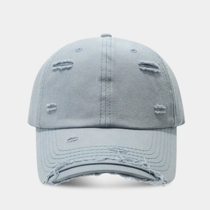 Detailed view of light blue distressed denim baseball cap with vintage frayed holes