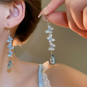 Detail of long silver tassel earrings with blue butterflies and a teardrop crystal drop