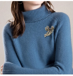 Detail of a sparkling rhinestone bow brooch pinned on a blue turtleneck sweater