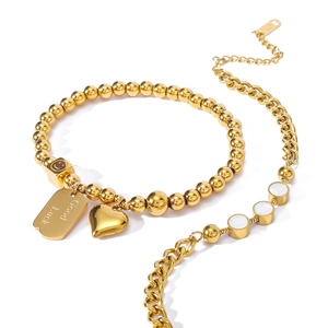 Detail of gold titanium bracelet set with heart charm and Good Luck engraved tag