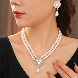 Close-up of double-layer pearl necklace and drop earrings with sparkling rhinestones