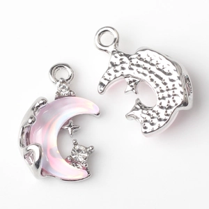 Macro detail of silver moon and star pendant with pink resin and white rhinestones