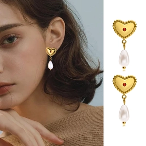 Close-up of vintage gold heart earrings with red gemstones and teardrop pearls