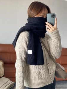 Close-up of a warm black knitted winter scarf worn by a person in a mirror selfie style