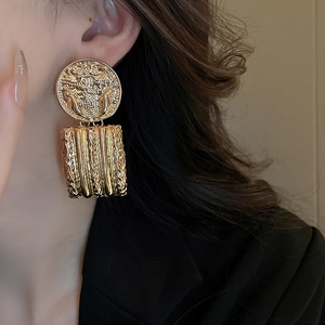 Macro detail of vintage gold embossed baroque style earrings showing geometric textures