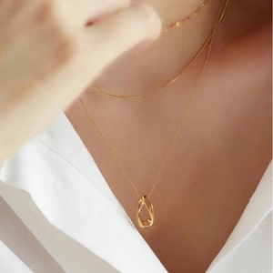 Collana con ciondolo a goccia dorata stile francese indossata su camicia bianca elegante