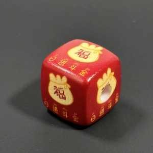 Macro shot of a red acrylic cube bead featuring a gold lucky pouch and Chinese lettering