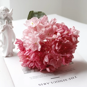 Detailed close-up of pink artificial hydrangea flowers on a magazine with angel statue