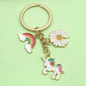 Detailed close-up of unicorn, rainbow, and daisy charms on a gold metal keychain