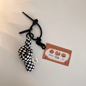 Detail view of a black and white checkered knot plush charm with a plastic chain link