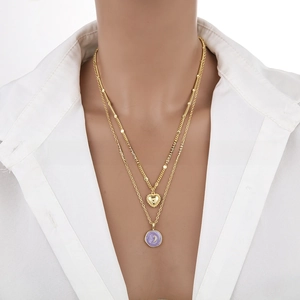Detail of layered gold necklace featuring a heart charm and purple crescent moon pendant