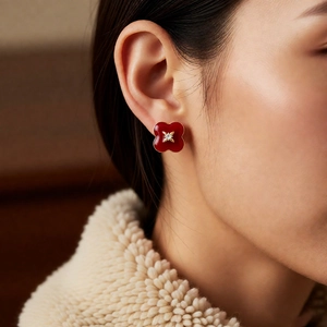 Close-up of vintage red clover stud earrings with gold trim worn by a model