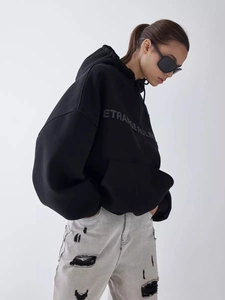 Detail of oversized black hoodie with ETRANGE RULE print and ripped grey jeans