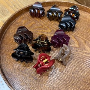 Close-up of assorted acetate claw clips in vintage colors on a wooden tray with gold springs