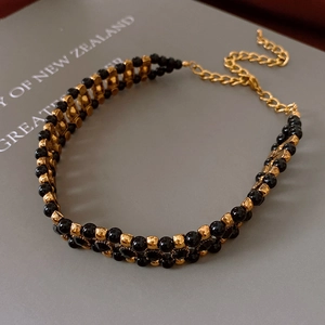 Detail of vintage black and gold beaded necklace with adjustable chain on a book