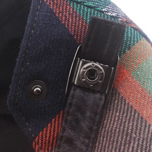 Macro detail of plaid wool fabric and leather strap with vintage buckle on the cap