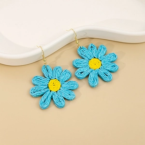 Gros plan sur des boucles d'oreilles marguerites tressées avec pétales bleus