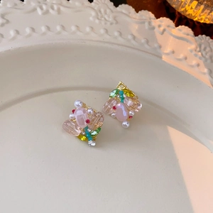 Detailaufnahme von Blumenohrringen mit rosa und gelben Kristallen in einer Keramikschale