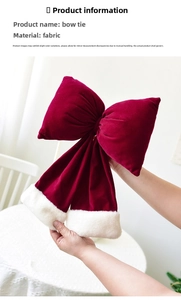 Detail of a large red velvet Christmas bow with white faux fur trim held by hand